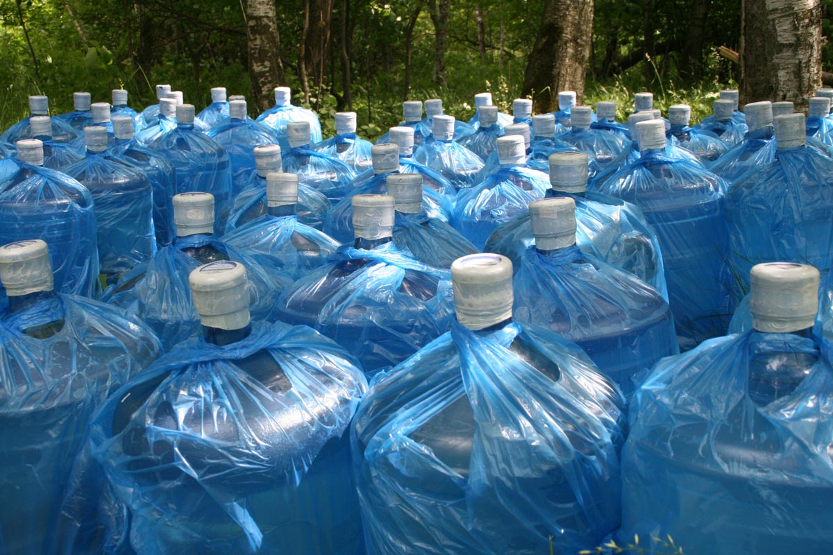 Multiple five gallon jugs of water sitting outside for storage.