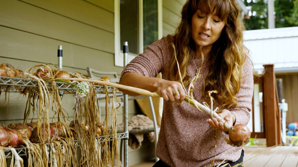 A woman showing an onion stalk that's not fully dried.