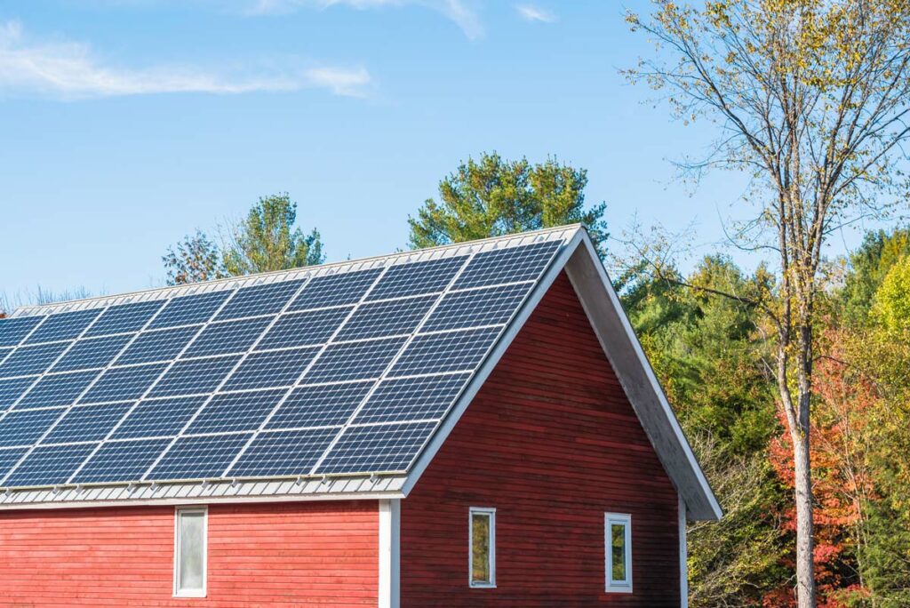 Solar panels on the roof of a red barn.