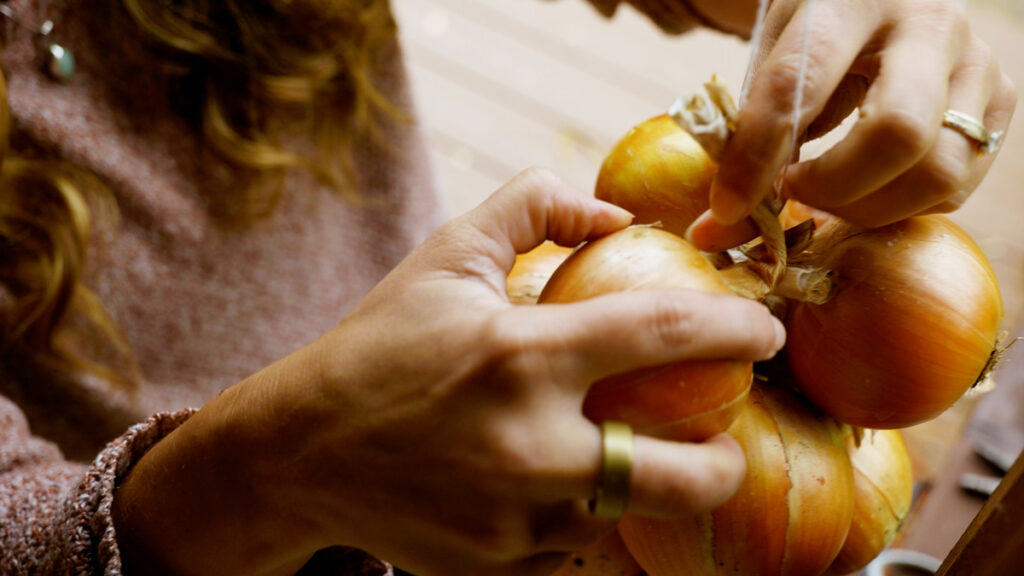 A woman stringing an onion for long-term storage.