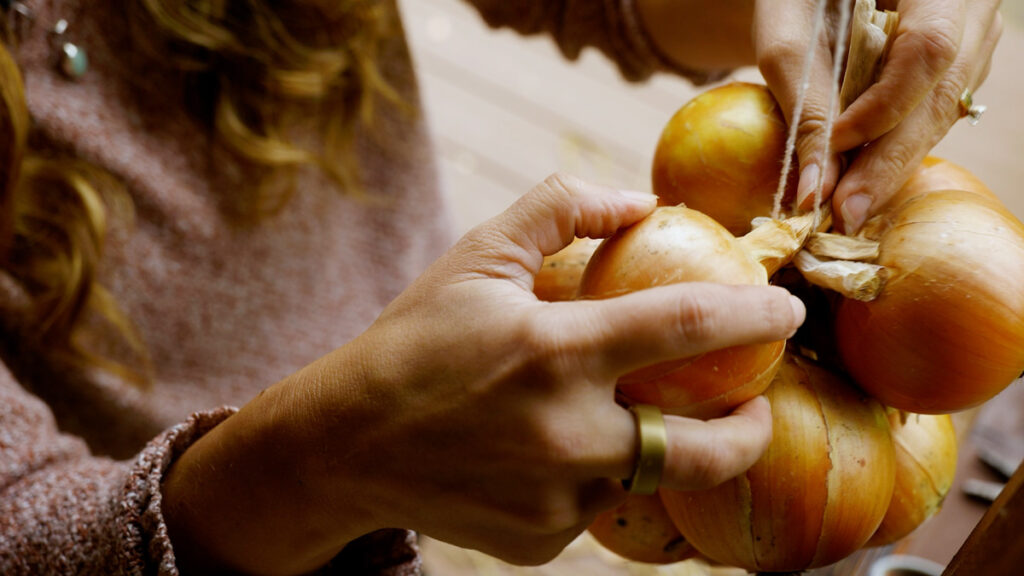 A woman stringing an onion for long-term storage.