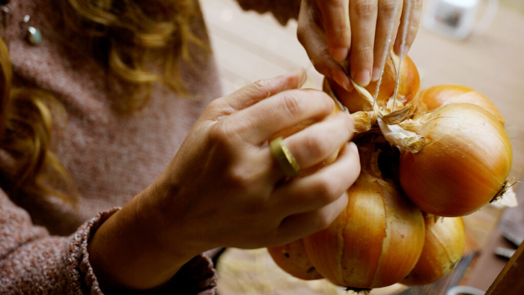 A woman stringing an onion for long-term storage.