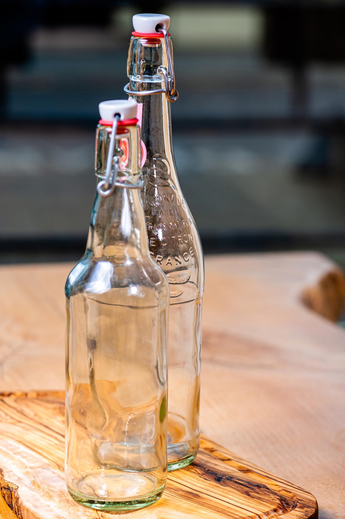 Swing top glass bottles on a wooden counter.