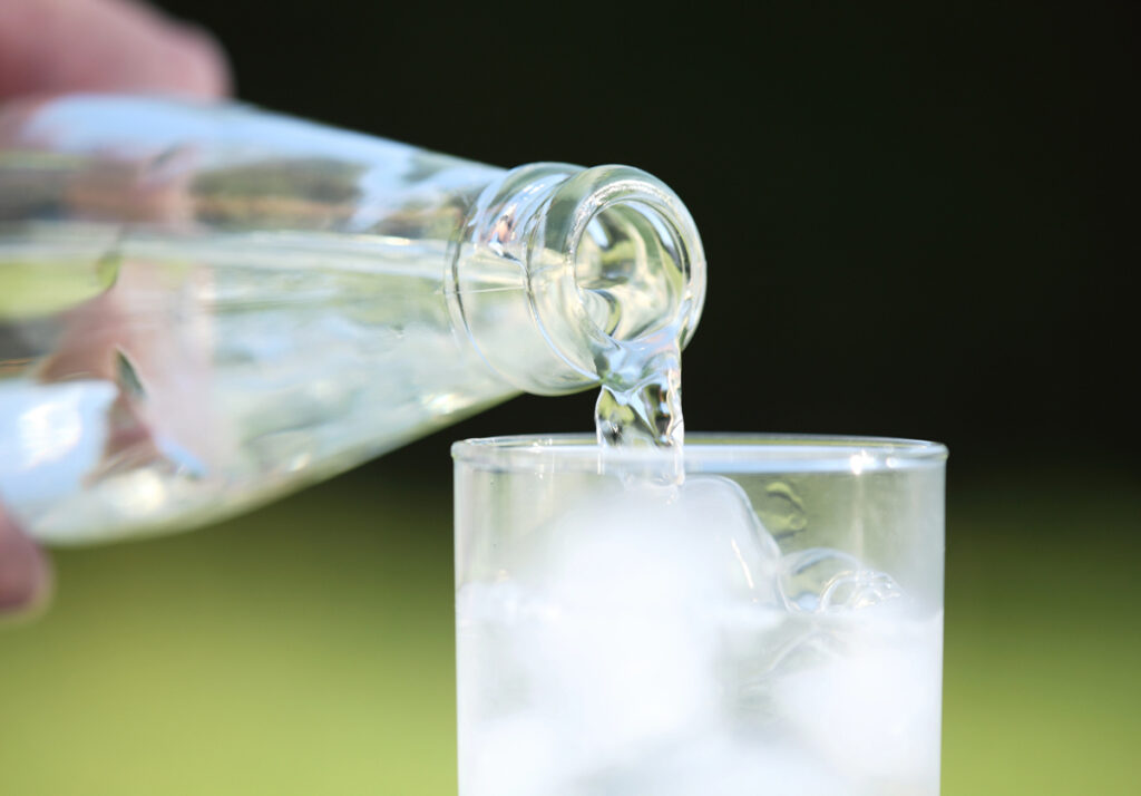 A bottle of water being poured into a glass.