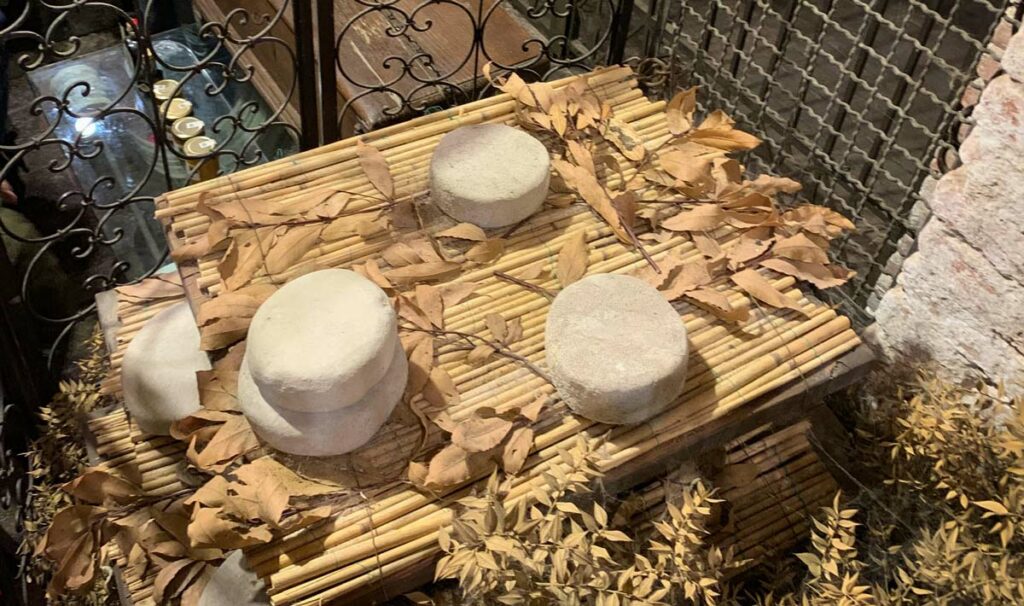 Cheese maturing on a rack outdoors.