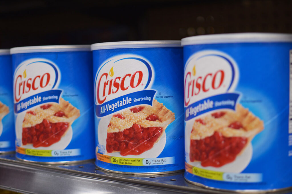 Three containers of Crisco on a shelf.