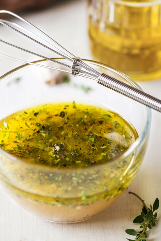 Herb oil in a glass bowl with whisk.