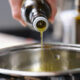 Olive oil being poured into a saucepan.