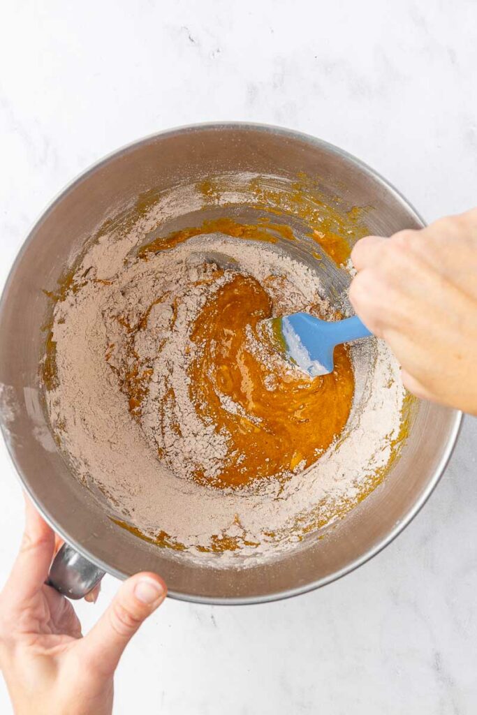 Pumpkin roll batter being mixed in the bowl of a stand mixer.