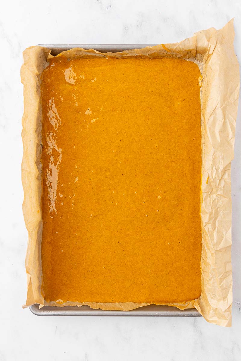The batter for a pumpkin roll cake in a 9x13 sheet pan.