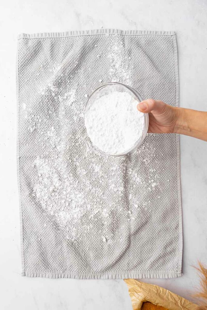 Powdered sugar being sprinkled on a tea towel.