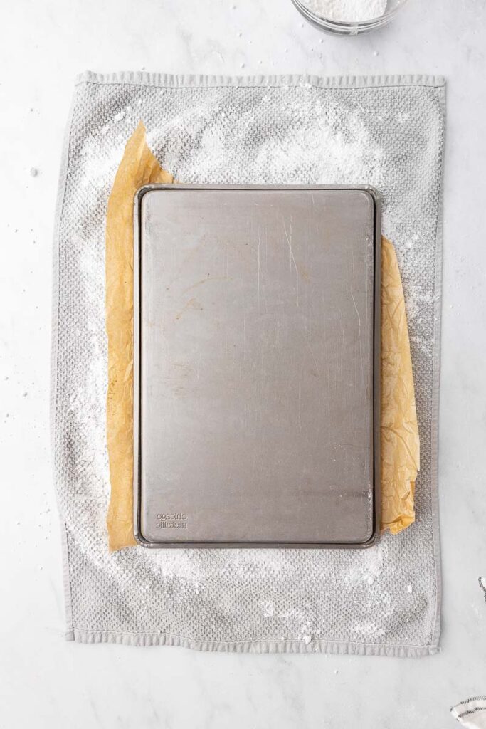 A pumpkin roll cake being dumped out of a sheet pan.