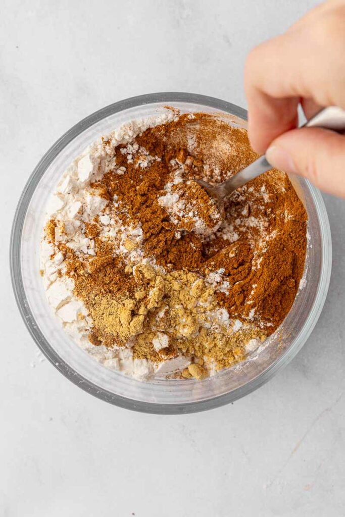 Dry ingredients for a homemade pumpkin roll in a glass bowl.