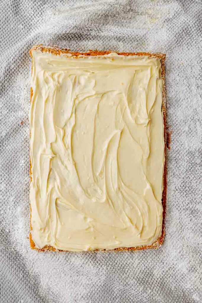 Frosting spread on top of a sheet of pumpkin cake.