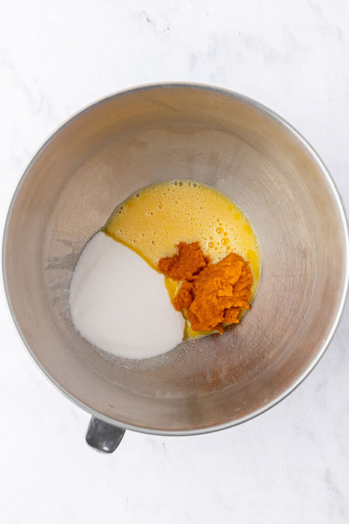 Wet ingredients for pumpkin roll in the bowl of a stand mixer.