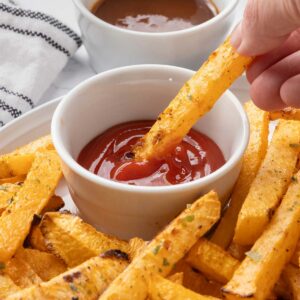 A rutabaga fry being dipped into ketchup.