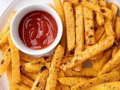 Rutabaga fries on a white plate with dipping sauces.