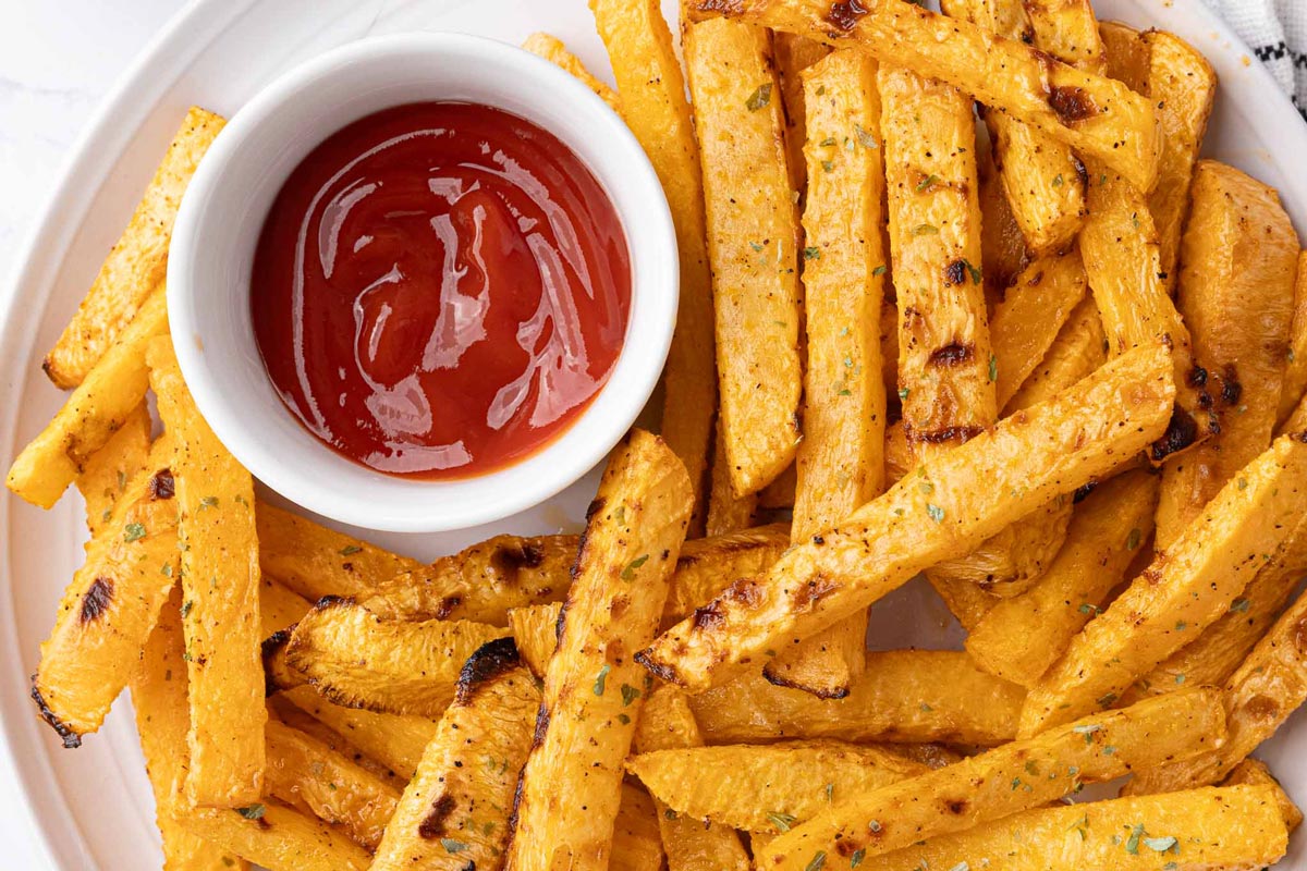 Rutabaga fries on a white plate with dipping sauces.