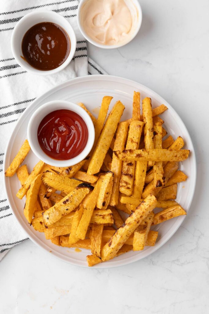 Rutabaga fries on a white plate with dipping sauces.