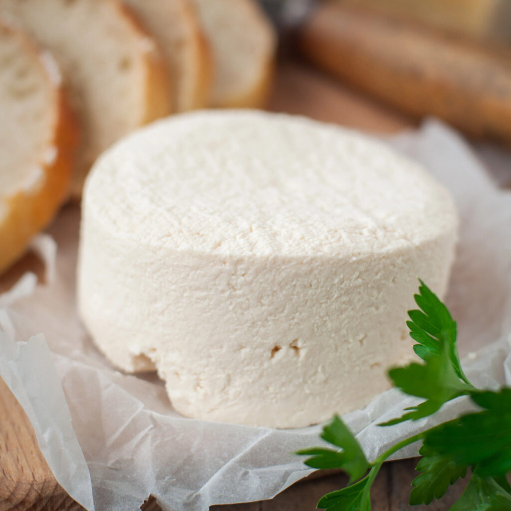 Soft chevre cheese on a wooden cutting board.