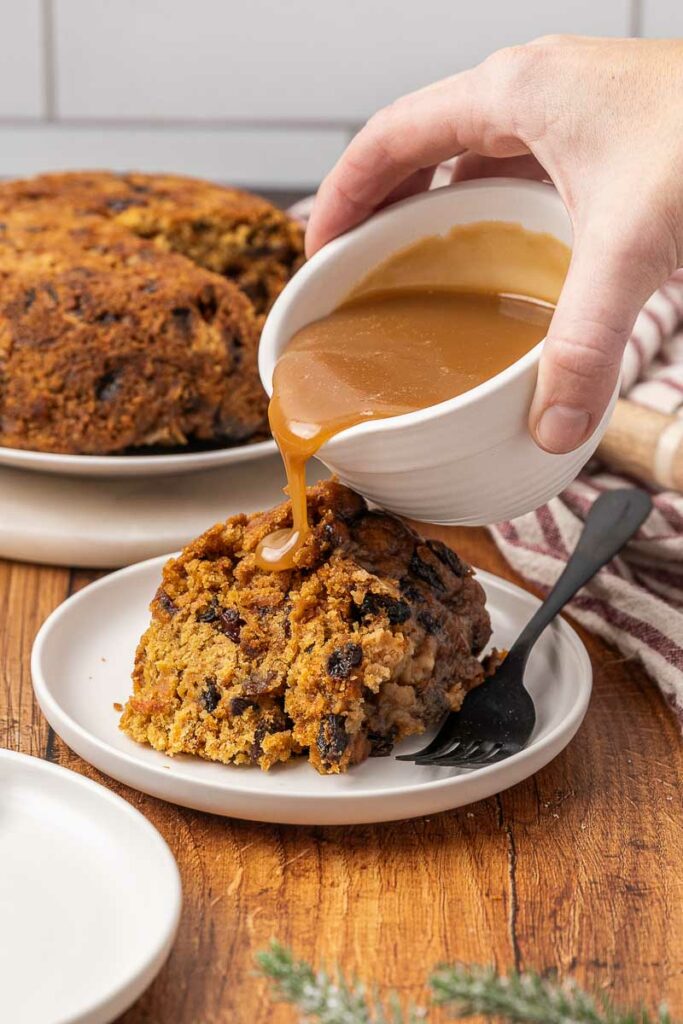 Christmas pudding being drizzled with brown sugar sauce.