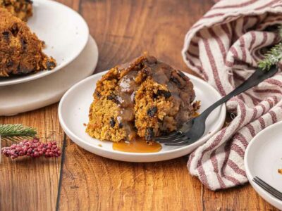 Christmas pudding served on a white plate with brown sugar sauce.