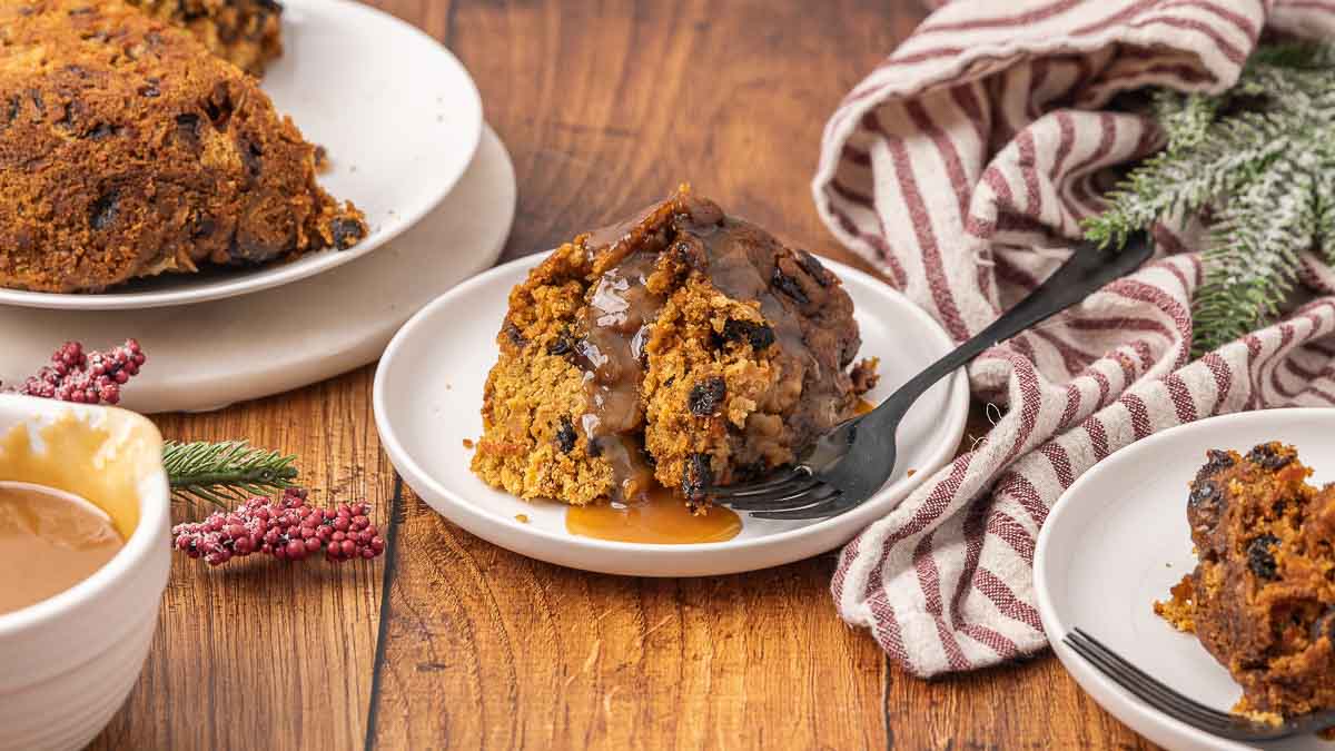 Christmas pudding served on a white plate with brown sugar sauce.