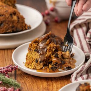 Christmas pudding served on a white plate with brown sugar sauce.