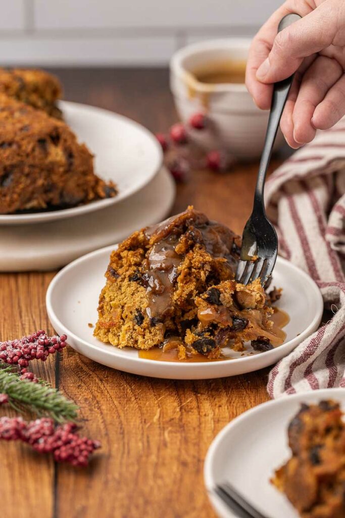 Christmas pudding served on a white plate with brown sugar sauce.