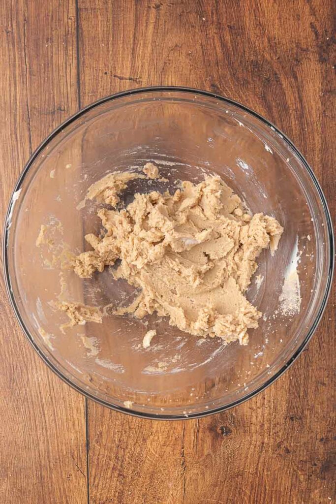 Christmas pudding batter being made in a clear glass bowl.