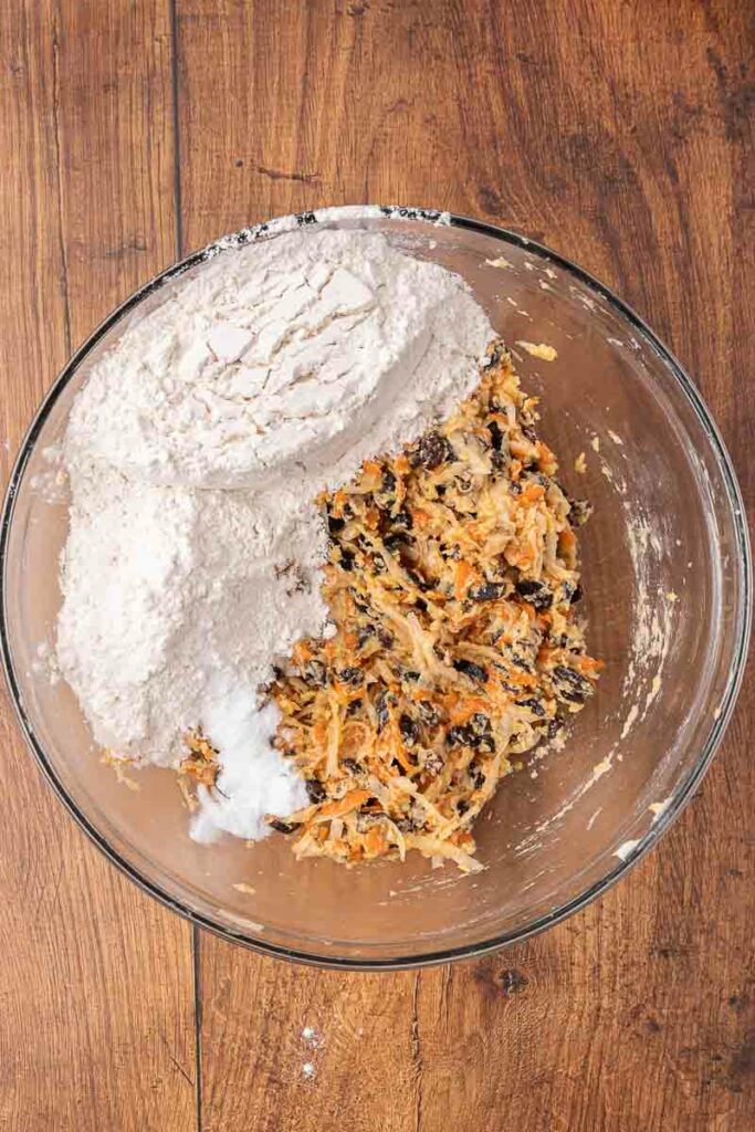 Christmas pudding batter being made in a clear glass bowl.