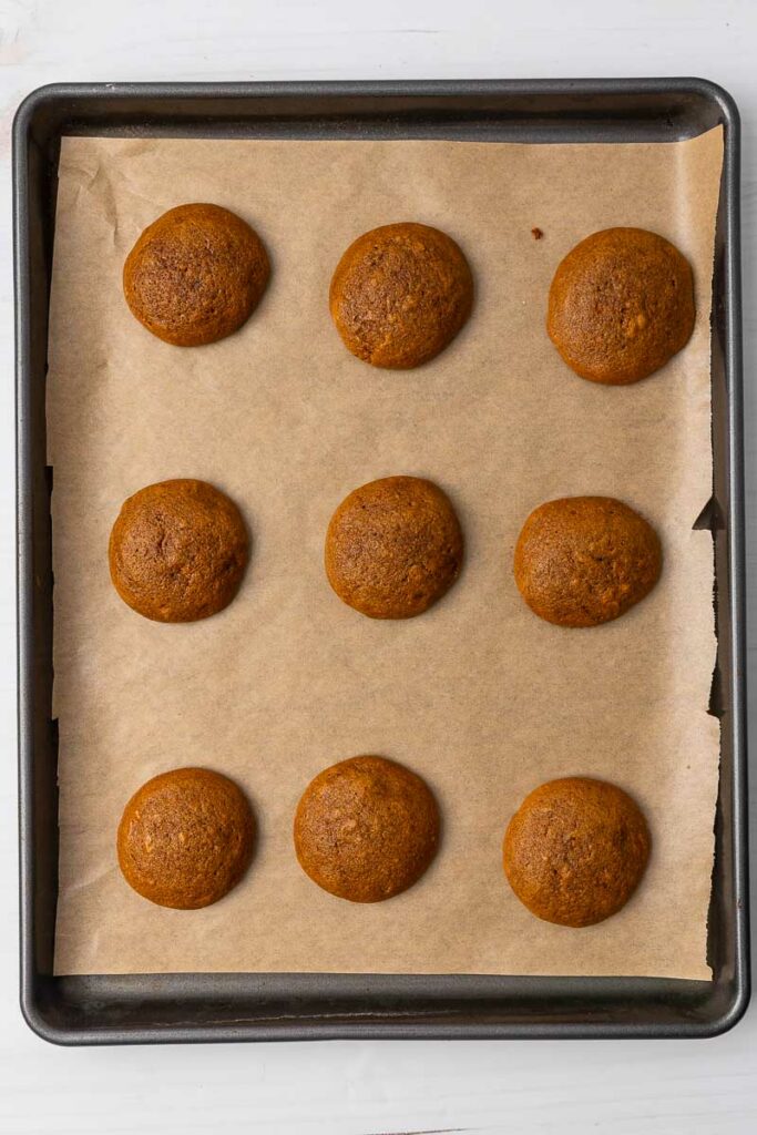 Baked ginger cream cookies on a parchment paper lined cookie sheet.