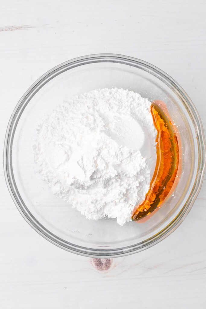 Ingredients for making maple icing in a glass bowl.