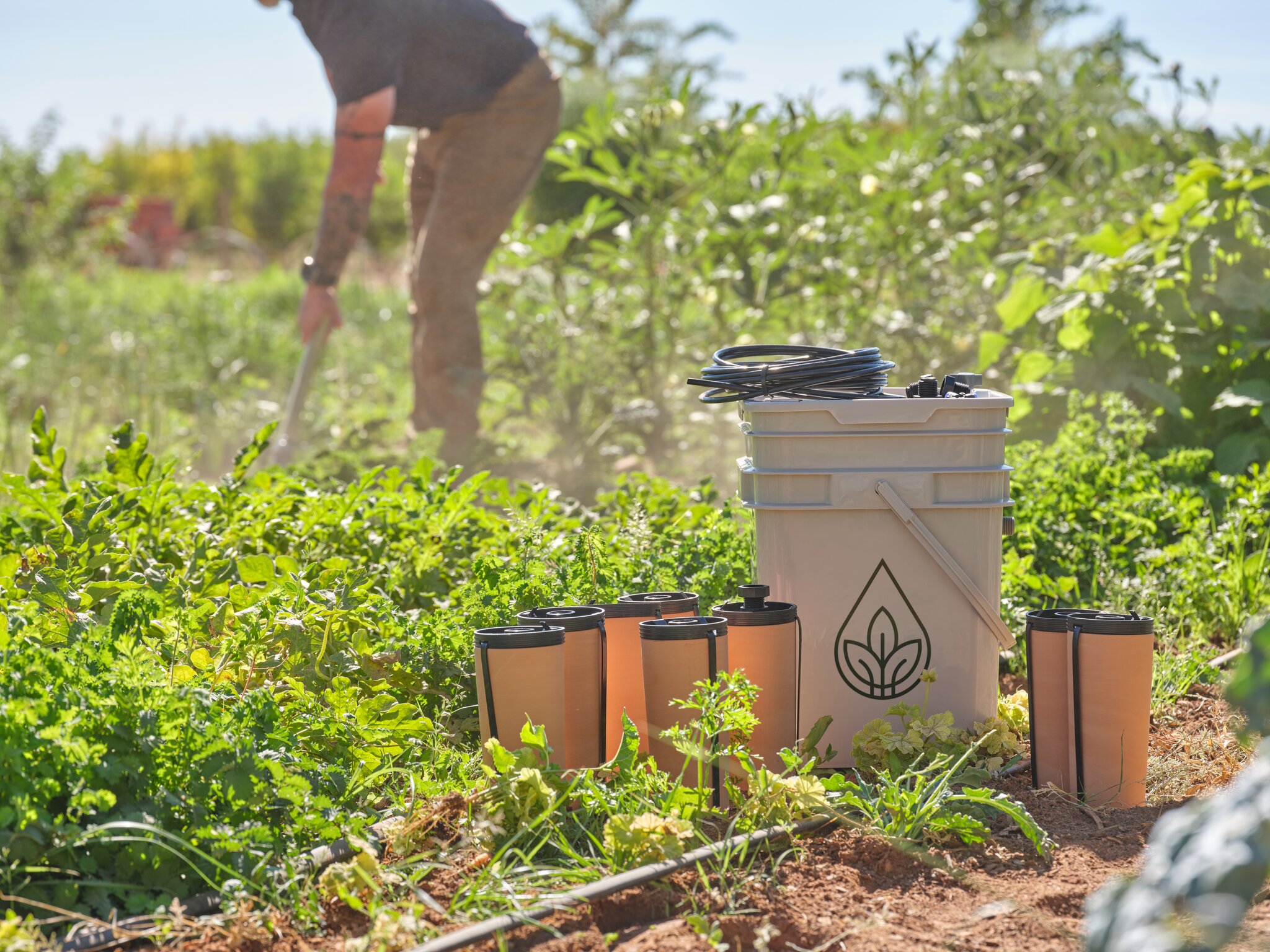 Olla watering pots with a man working in the garden.