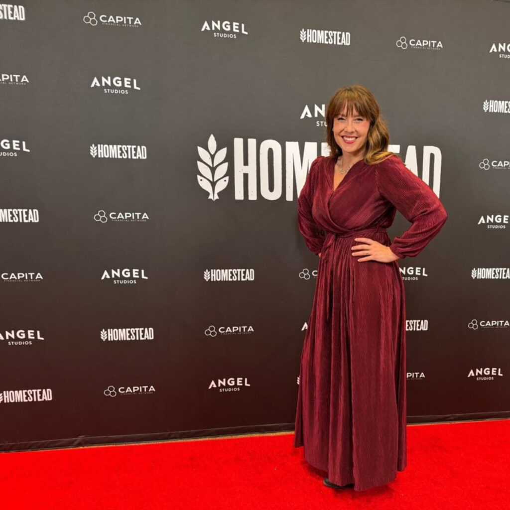 A woman in a long dress standing on the red carpet.