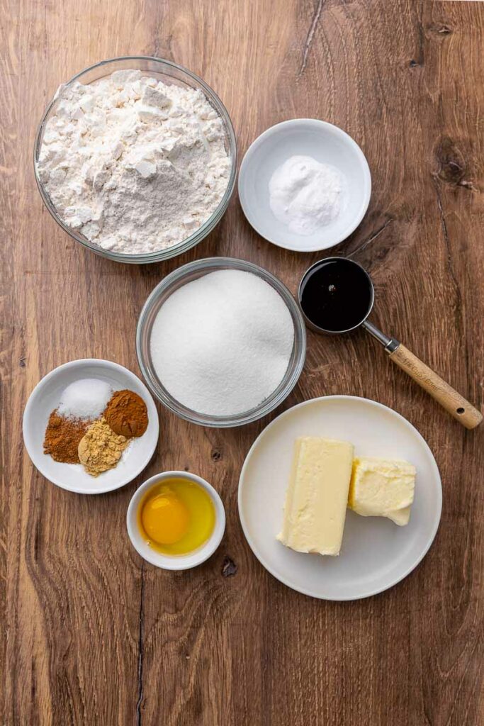 Ingredients for molasses cookies laid out in bowls on the counter.