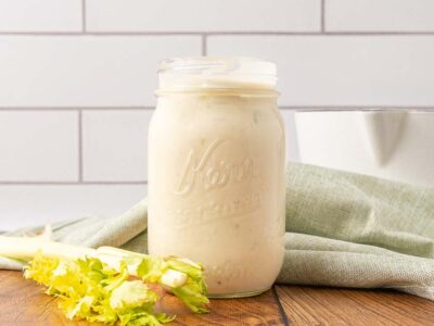 A Mason jar of cream of celery soup on a wooden counter.