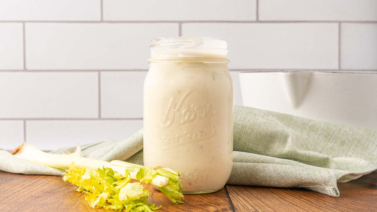 A Mason jar of cream of celery soup on a wooden counter.