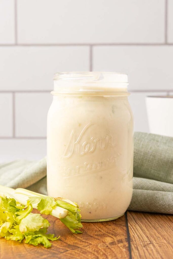 A Mason jar of cream of celery soup on a wooden counter.