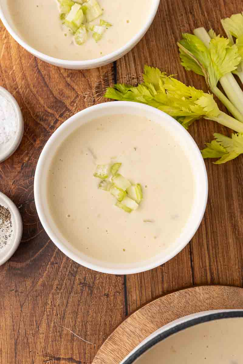 A bowl of cream of celery soup on a wooden table.