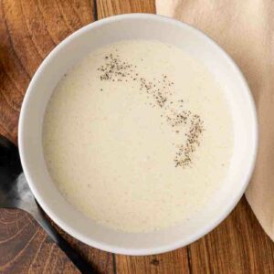 A bowl of cream of chicken soup on a wooden counter.