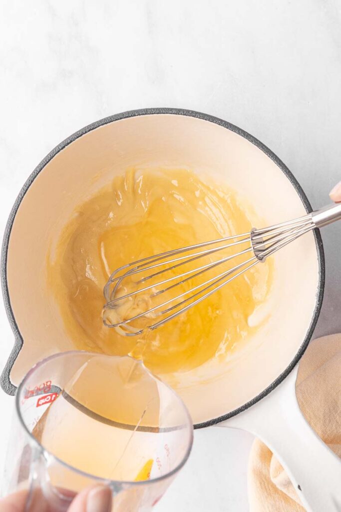 Chicken broth being poured into a roux for cream of chicken soup.