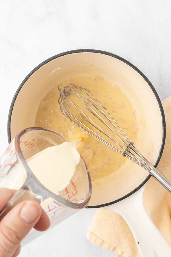 Cream being poured into a cream of onion soup.