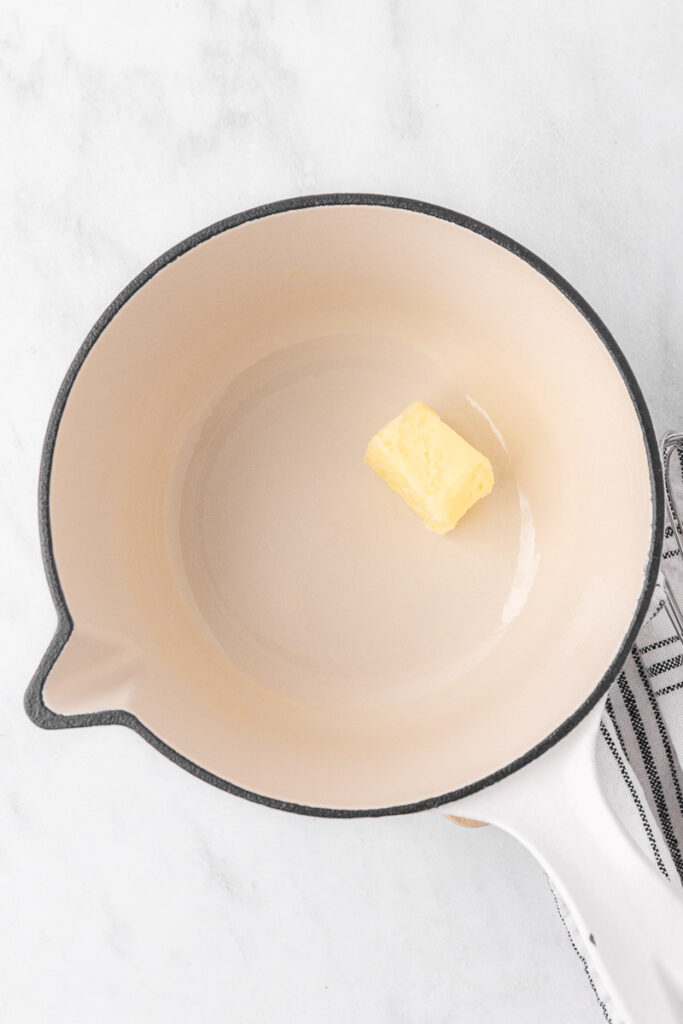 Butter melting in a large heavy-bottomed pan.