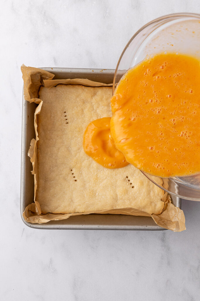 Papaya custard filling being poured over a shortbread cookie crust.