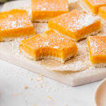 Papaya bars on a white cutting board, one with a bite taken out.