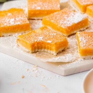 Papaya bars on a white cutting board, one with a bite taken out.