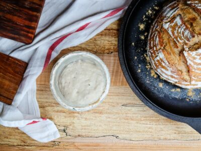 Sourdough loaf of bread and a jar of sourdough starter.