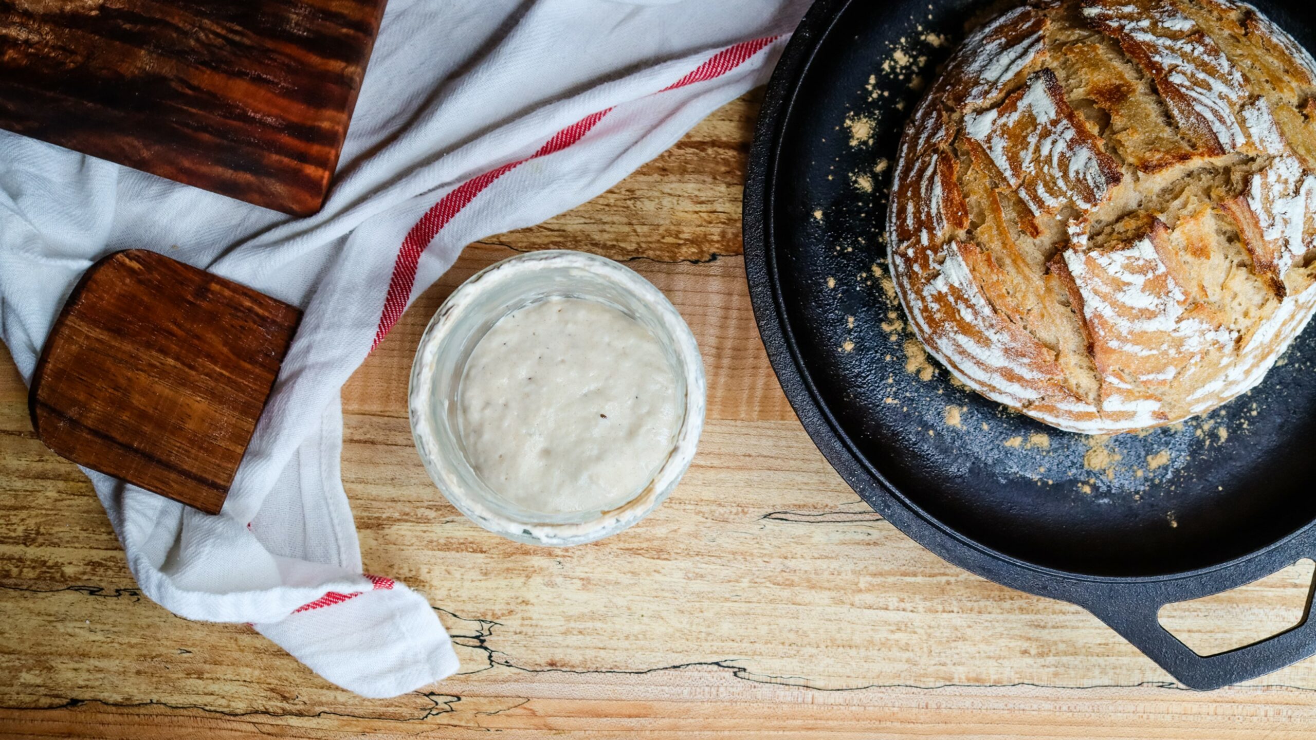 Sourdough loaf of bread and a jar of sourdough starter.