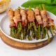 Bacon wrapped asparagus on a white plate.